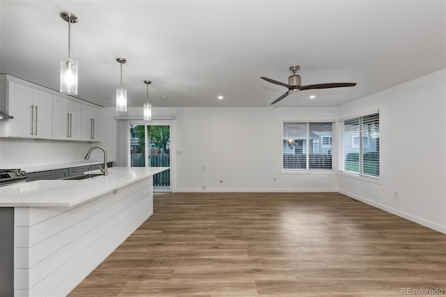 kitchen with a sink, a ceiling fan, light countertops, recessed lighting, and baseboards