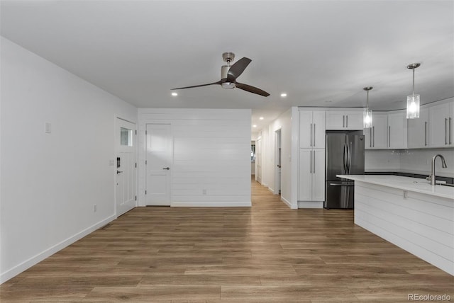 kitchen with stainless steel fridge, ceiling fan, recessed lighting, a sink, and light countertops