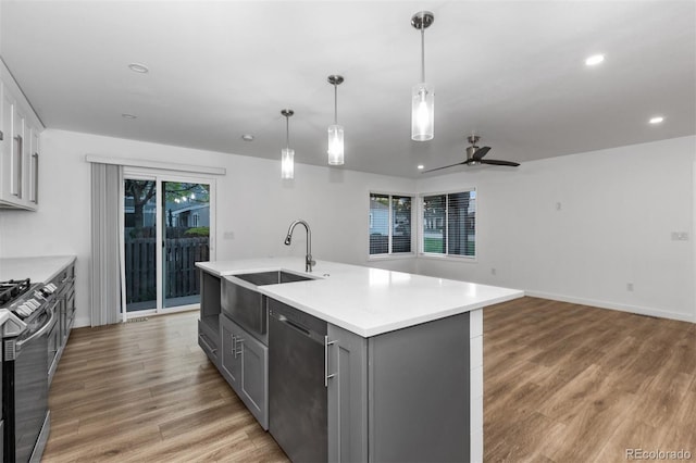 kitchen featuring stainless steel appliances, gray cabinetry, a sink, ceiling fan, and light countertops