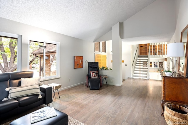 10572 E Orchard Pl, Englewood, CO 80111 - living room featuring stairway, light wood-type flooring, baseboards, high vaulted ceiling, and a textured ceiling