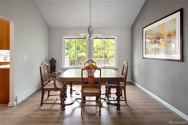 10572 E Orchard Pl, Englewood, CO 80111 - dining space featuring a chandelier, wood finished floors, vaulted ceiling, a textured ceiling, and baseboards