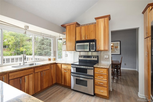 10572 E Orchard Pl, Englewood, CO 80111 - kitchen featuring stainless steel appliances, a sink, vaulted ceiling, light wood-style floors, and plenty of natural light