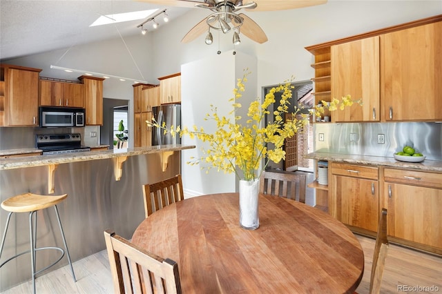 10572 E Orchard Pl, Englewood, CO 80111 - kitchen featuring stainless steel appliances, vaulted ceiling, a breakfast bar, ceiling fan, and a skylight