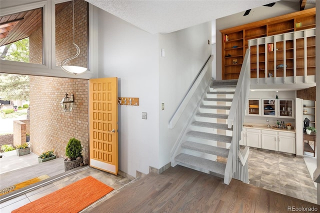 10572 E Orchard Pl, Englewood, CO 80111 - staircase with baseboards, a textured ceiling, brick wall, and wood finished floors