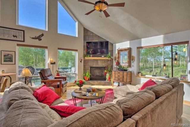 living room with a tile fireplace, ceiling fan, high vaulted ceiling, and wood-type flooring