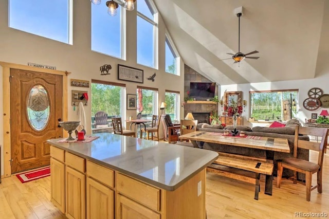 kitchen featuring a center island, a stone fireplace, a healthy amount of sunlight, and light hardwood / wood-style flooring