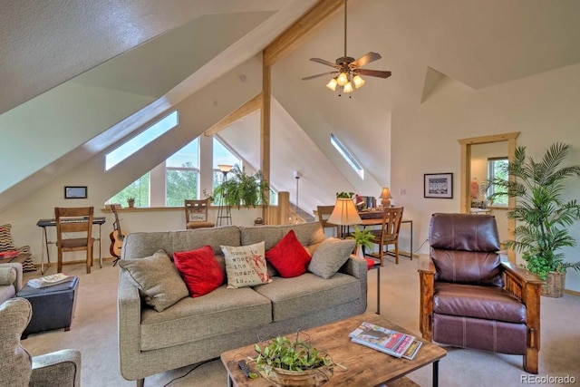 living room featuring light carpet, a skylight, ceiling fan, high vaulted ceiling, and beamed ceiling