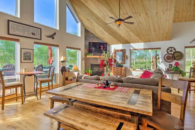 living room with ceiling fan, a tile fireplace, light hardwood / wood-style flooring, high vaulted ceiling, and wooden ceiling