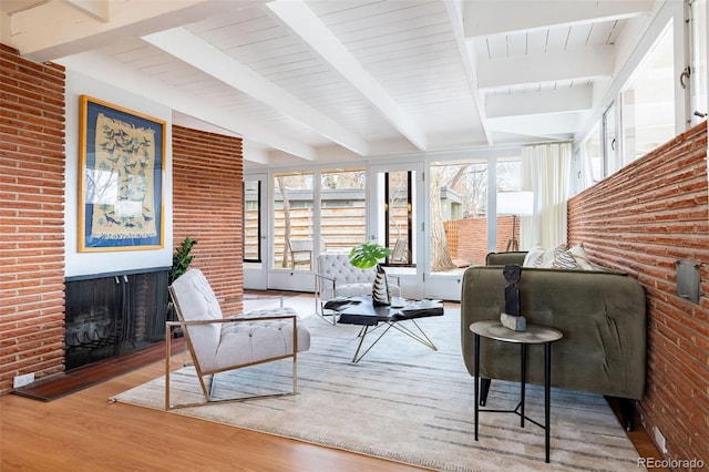 living room featuring beam ceiling, hardwood / wood-style flooring, and brick wall