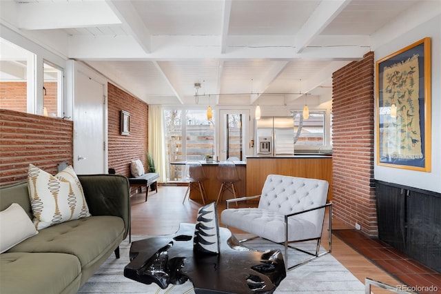 living room featuring beamed ceiling, brick wall, and wood-type flooring