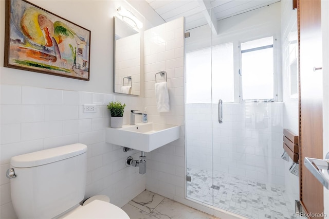 bathroom with toilet, a shower with shower door, sink, and tile walls