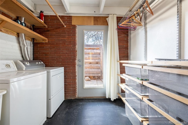 laundry area featuring brick wall and washer and clothes dryer