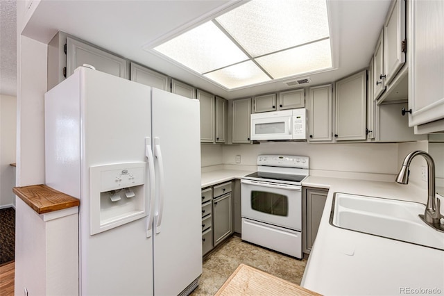 kitchen featuring white appliances, gray cabinets, and sink