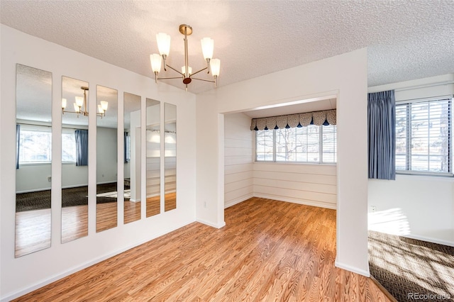 unfurnished room featuring a textured ceiling, a chandelier, and plenty of natural light