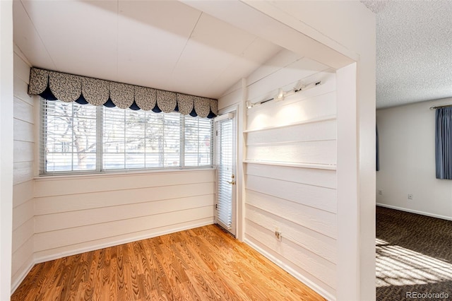 unfurnished room featuring a textured ceiling, wood walls, and hardwood / wood-style flooring