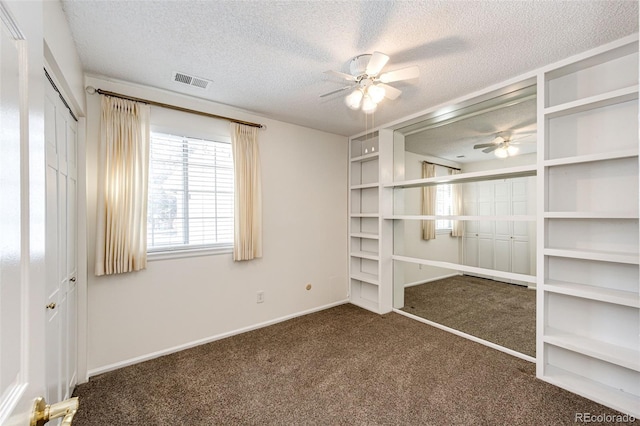 unfurnished bedroom featuring a textured ceiling, ceiling fan, and dark carpet