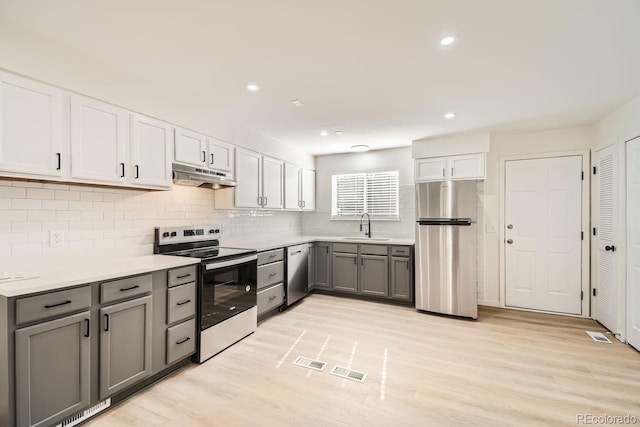 kitchen with sink, gray cabinets, light wood-type flooring, white cabinetry, and stainless steel appliances