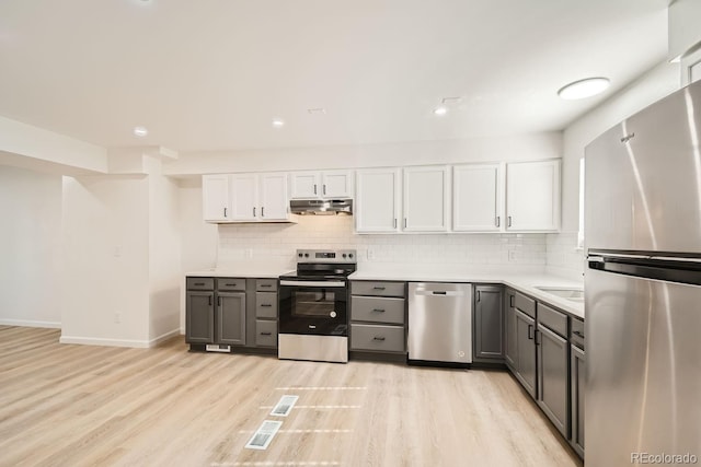 kitchen with backsplash, gray cabinets, appliances with stainless steel finishes, light hardwood / wood-style floors, and white cabinetry