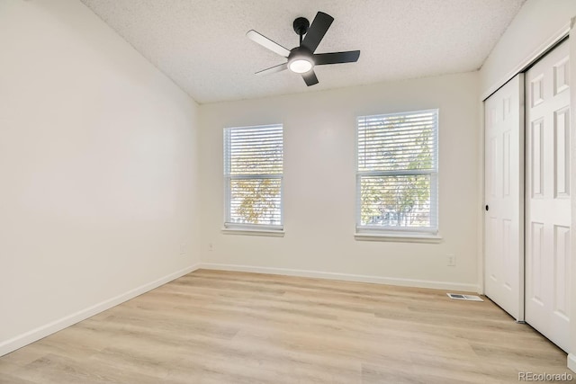 unfurnished bedroom with a textured ceiling, light hardwood / wood-style floors, and ceiling fan