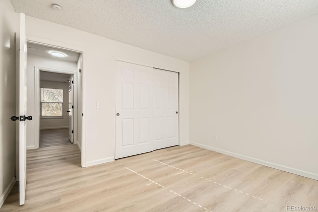 unfurnished bedroom with light wood-type flooring, a textured ceiling, and a closet