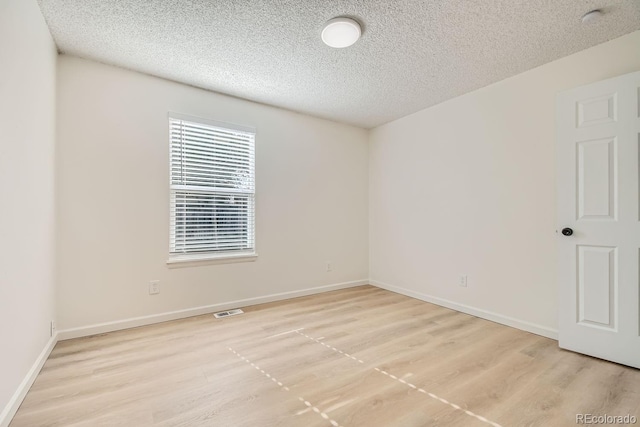 empty room with a textured ceiling and light wood-type flooring