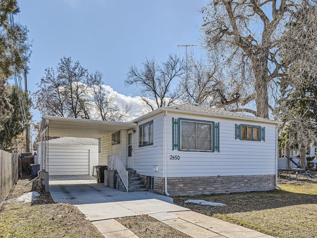 view of front of property featuring fence, concrete driveway, and an outdoor structure