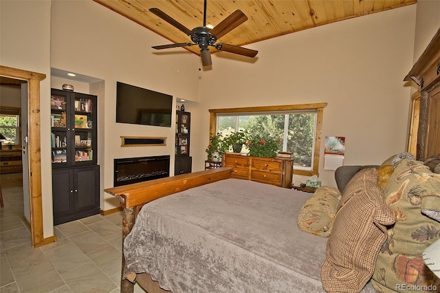 tiled bedroom with wood ceiling, ceiling fan, and a high ceiling