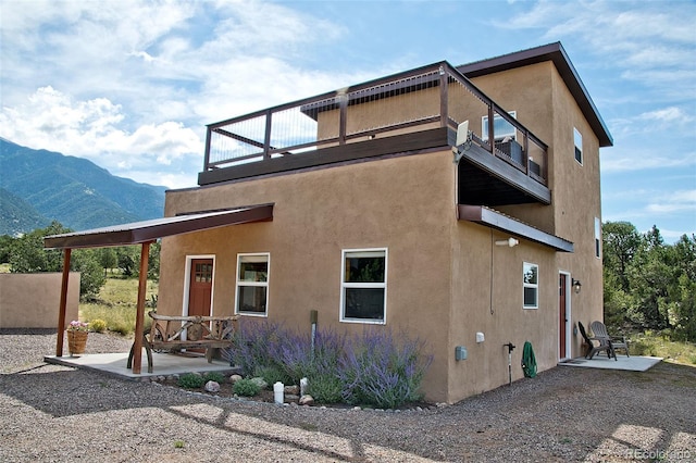 view of home's exterior with a balcony, a mountain view, and a patio