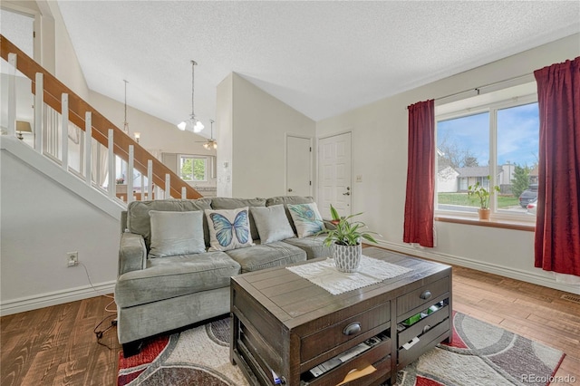 19140 E Milan Cir, Aurora, CO 80013 - living area featuring a textured ceiling, vaulted ceiling, wood finished floors, baseboards, and a notable chandelier