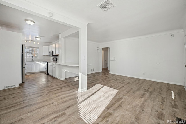 unfurnished living room with crown molding and light wood-type flooring