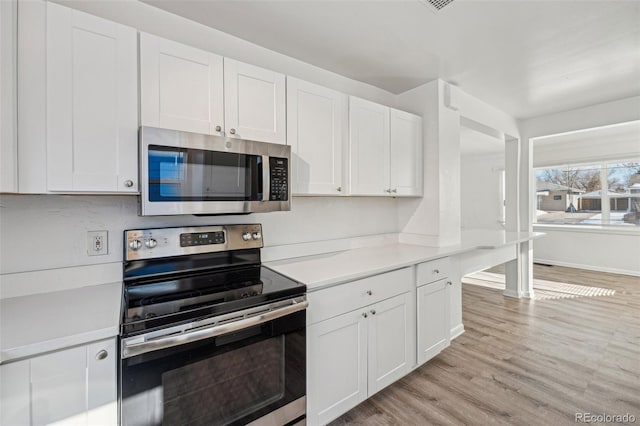 kitchen with white cabinetry, stainless steel appliances, and light hardwood / wood-style flooring