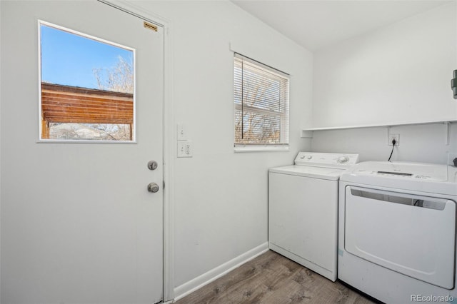 clothes washing area with washing machine and dryer, wood-type flooring, and a wealth of natural light