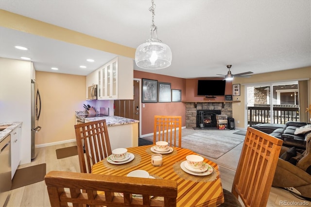 3482 S Eagle St Unit 102, Aurora, CO 80014 - dining room with a ceiling fan, light wood-style floors, baseboards, recessed lighting, and a stone fireplace