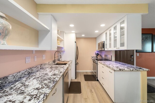 3482 S Eagle St Unit 102, Aurora, CO 80014 - kitchen with stainless steel appliances, a sink, open shelves, light wood-style flooring, and white cabinetry