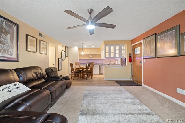 3482 S Eagle St Unit 102, Aurora, CO 80014 - living room featuring ceiling fan, carpet floors, baseboards, and a textured ceiling