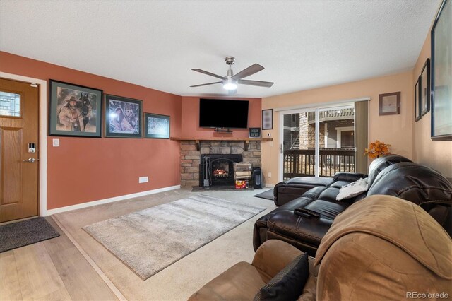 3482 S Eagle St Unit 102, Aurora, CO 80014 - living area with a ceiling fan, a stone fireplace, light wood-type flooring, baseboards, and a textured ceiling