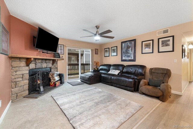 3482 S Eagle St Unit 102, Aurora, CO 80014 - living area with ceiling fan, baseboards, a stone fireplace, a textured ceiling, and wood finished floors