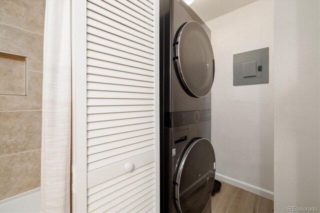 3482 S Eagle St Unit 102, Aurora, CO 80014 - laundry room featuring stacked washing machine and dryer, electric panel, wood finished floors, and baseboards
