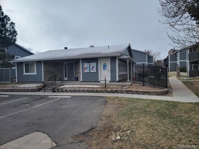 3482 S Eagle St Unit 102, Aurora, CO 80014 - view of front of property with fence, uncovered parking, and stone siding