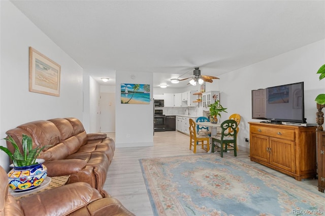 living room featuring ceiling fan, sink, and light hardwood / wood-style flooring