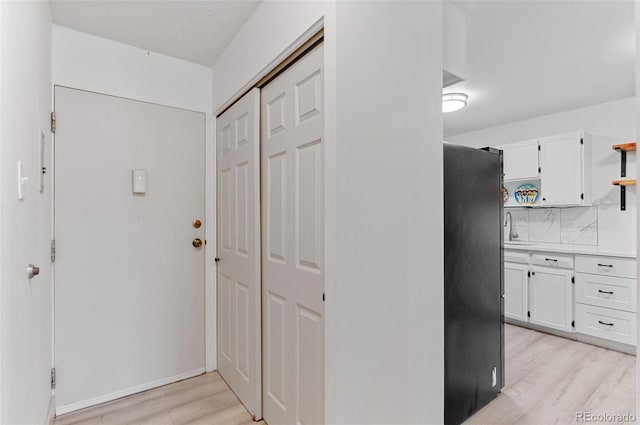 interior space with a textured ceiling, light hardwood / wood-style floors, and sink