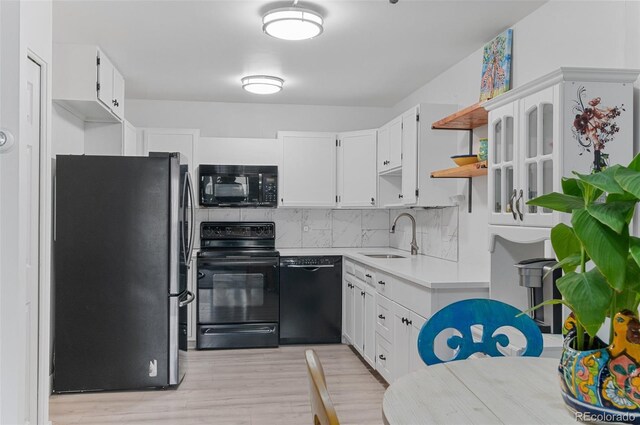 kitchen featuring sink, light hardwood / wood-style flooring, white cabinetry, and black appliances