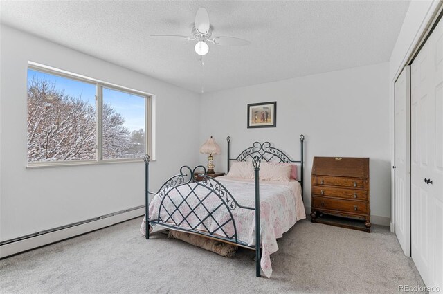 carpeted bedroom featuring ceiling fan, a closet, a baseboard radiator, and a textured ceiling