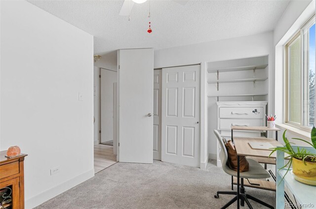 office space featuring ceiling fan, light colored carpet, and a textured ceiling