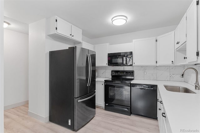 kitchen with light wood-style flooring, a sink, black appliances, light countertops, and tasteful backsplash