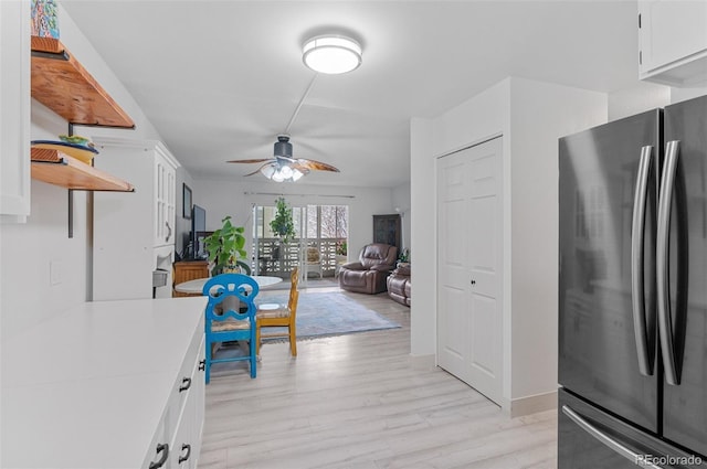 kitchen with freestanding refrigerator, white cabinetry, light countertops, and a ceiling fan