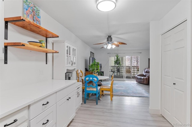 kitchen with light wood-style flooring, ceiling fan, white cabinetry, open shelves, and light countertops