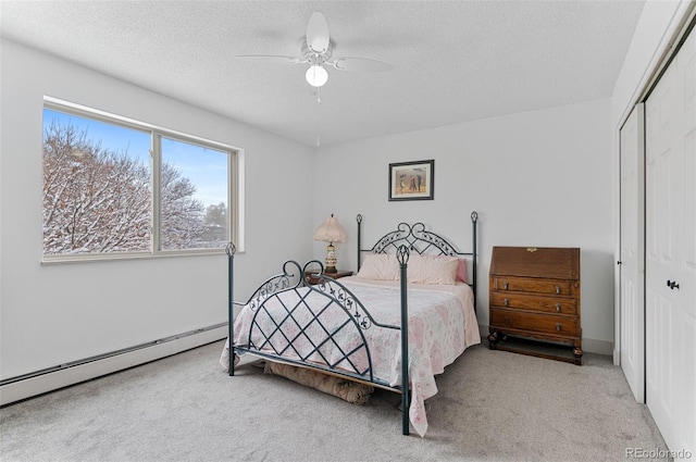 carpeted bedroom with a ceiling fan, a closet, a textured ceiling, and baseboard heating