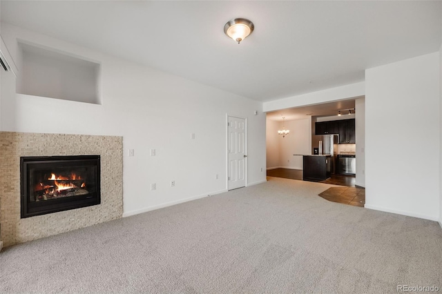 unfurnished living room featuring a notable chandelier and carpet flooring