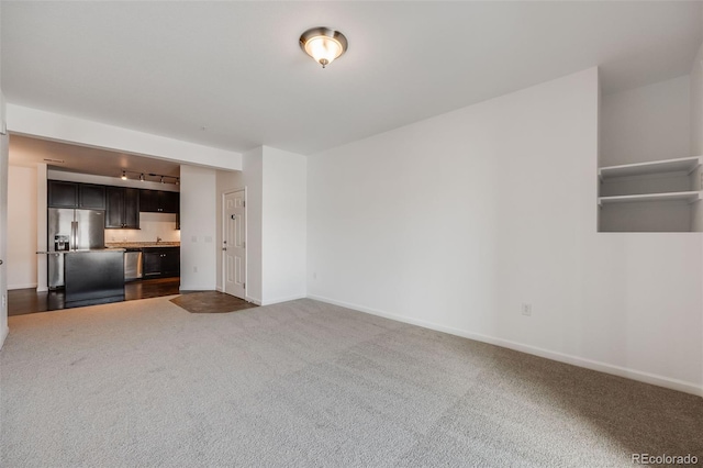 unfurnished living room featuring dark colored carpet and rail lighting